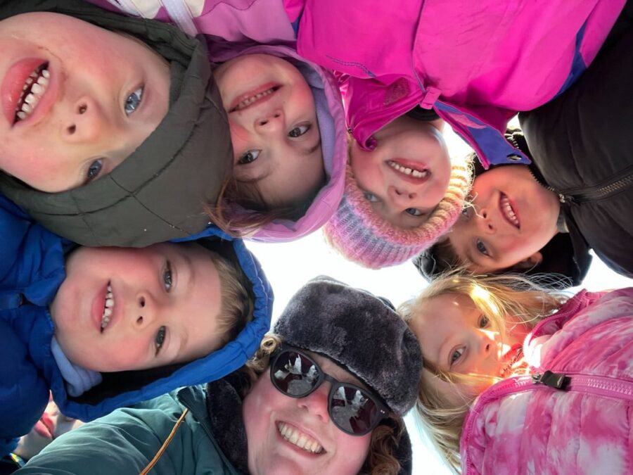Students leaning in over the camera with their heads touching and smiling.